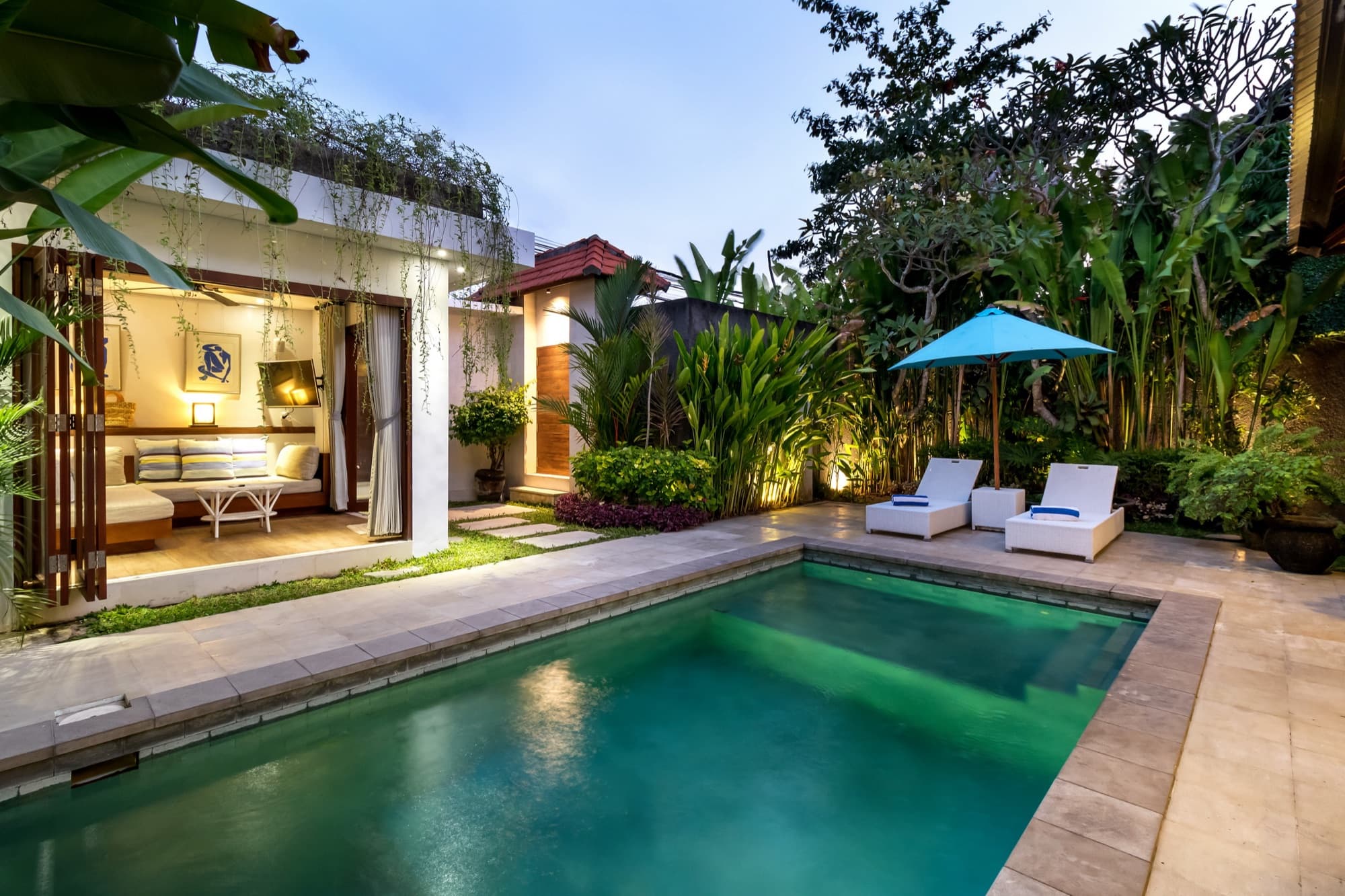 Villa Blue Bali — pool, sun loungers and a softly lit bale at twilight